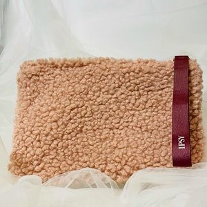 Pink faux sheepskin bag with maroon zipper/handle.